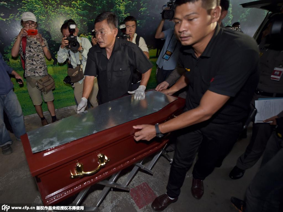 Thai police and workers shift a coffin containing the body of a Malaysian girl killed in a bomb blast outside a religious shrine, at the Institute of Forensic Medicine in Bangkok on August 19, 2015. A man suspected of planting a deadly bomb in Bangkok is part of a wider "network", Thailand's top policeman said August 19, as monks led prayers and reopened the shrine where 20 people were killed. AFP PHOTO / PORNCHAI KITTIWONGSAKUL